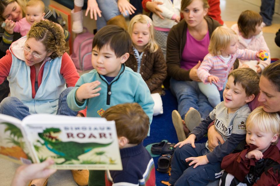 Children and Adults Sitting Listening to a book called Dinosaur Roar