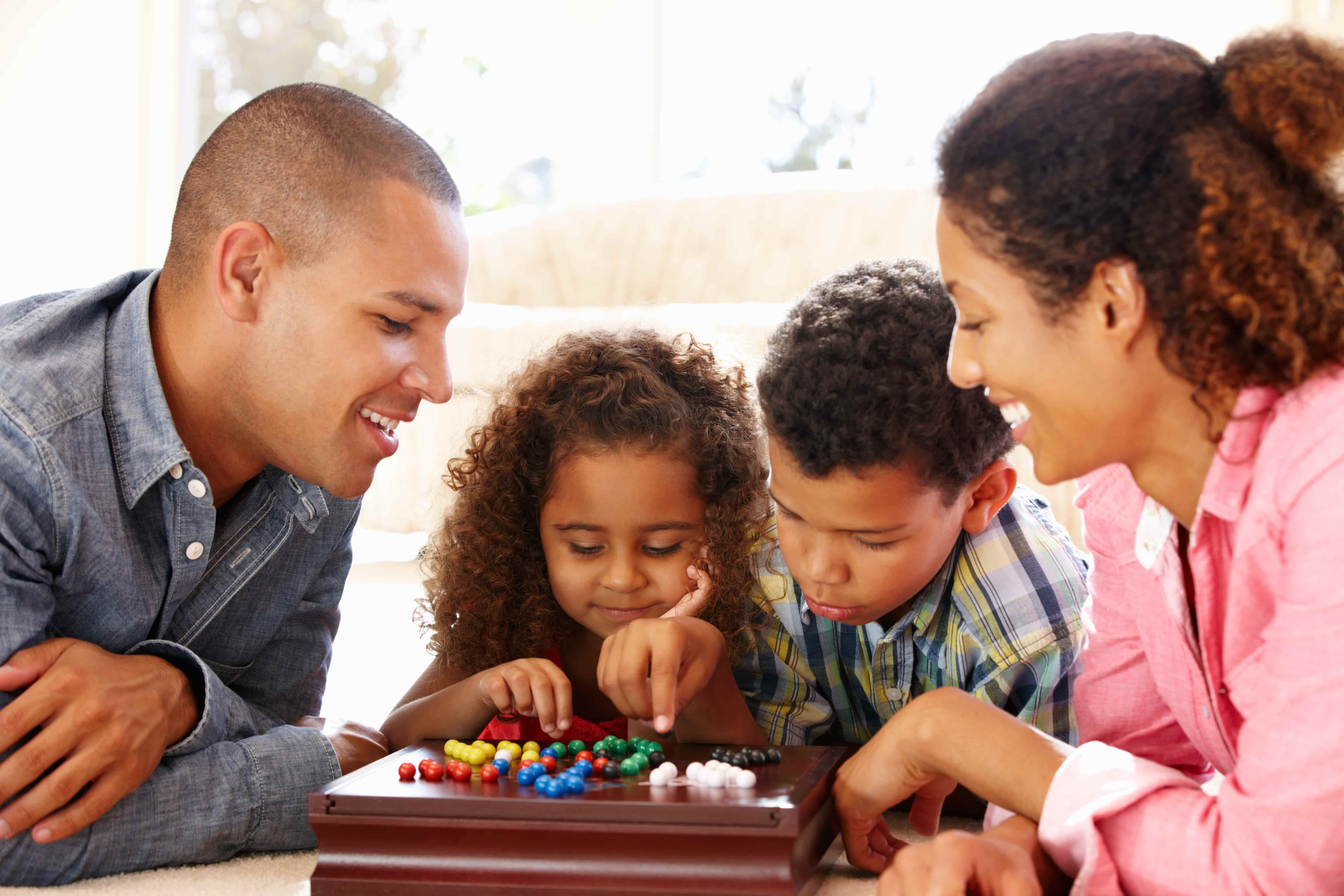 Families of 4 playing a marble game on the floor
