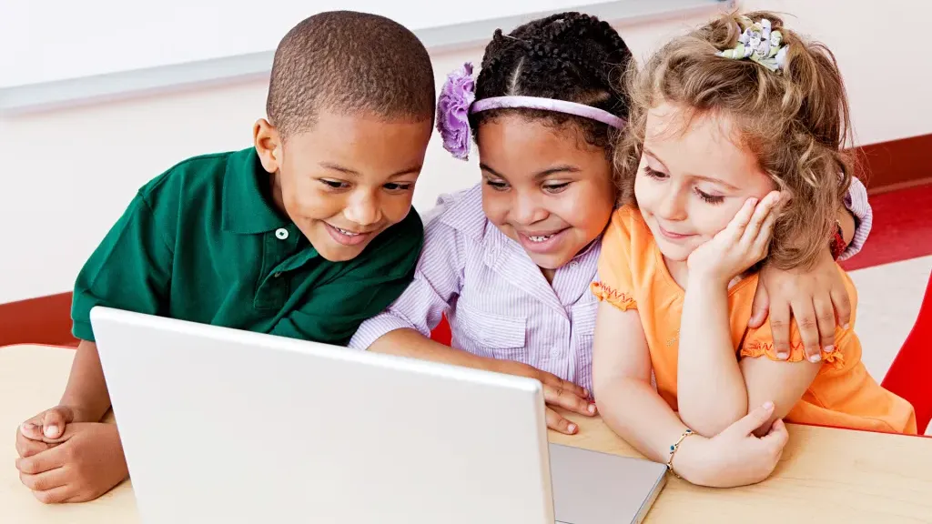 Three children playing togther on a laptop computer.