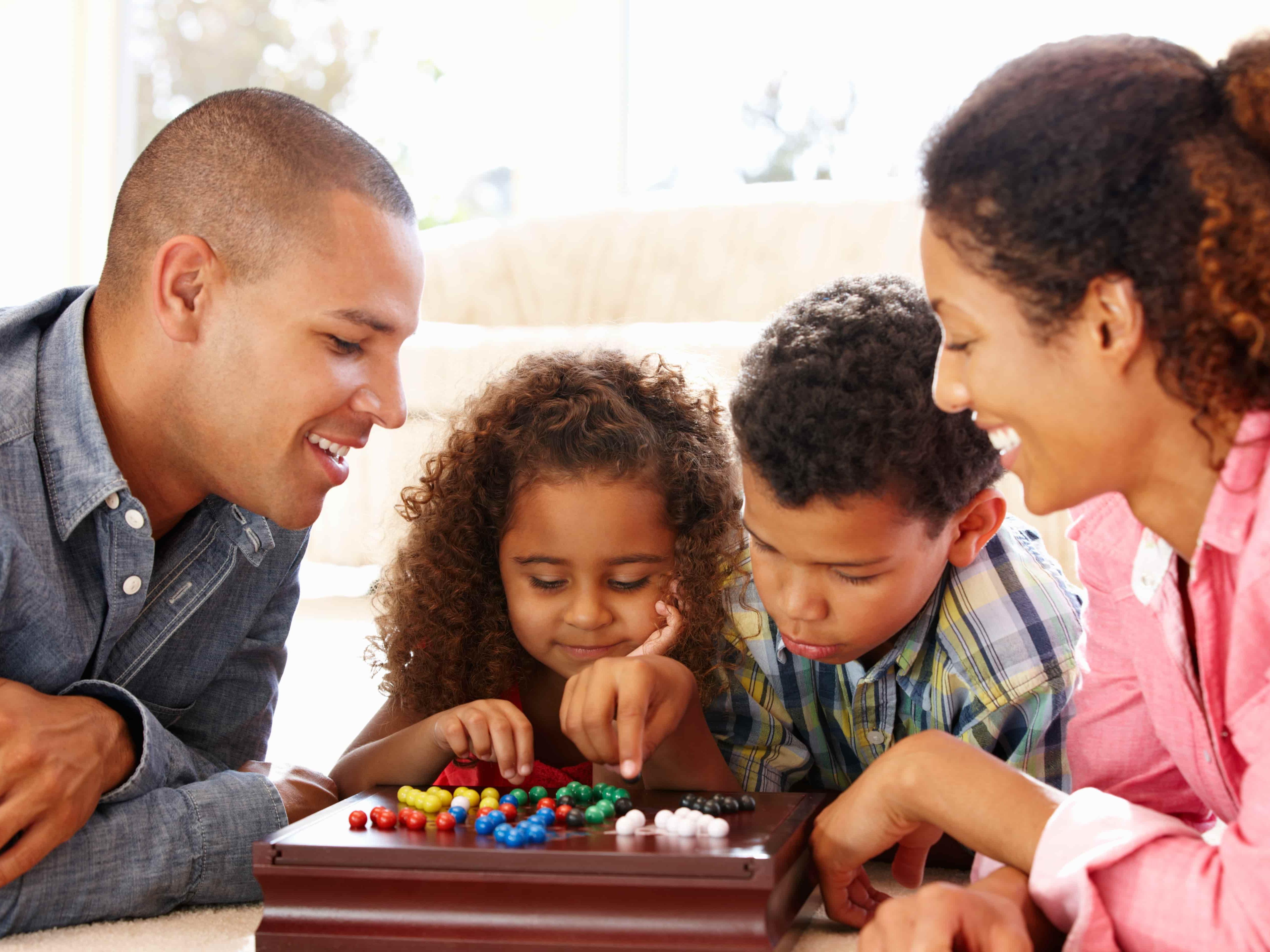 Families of 4 playing a marble game on the floor