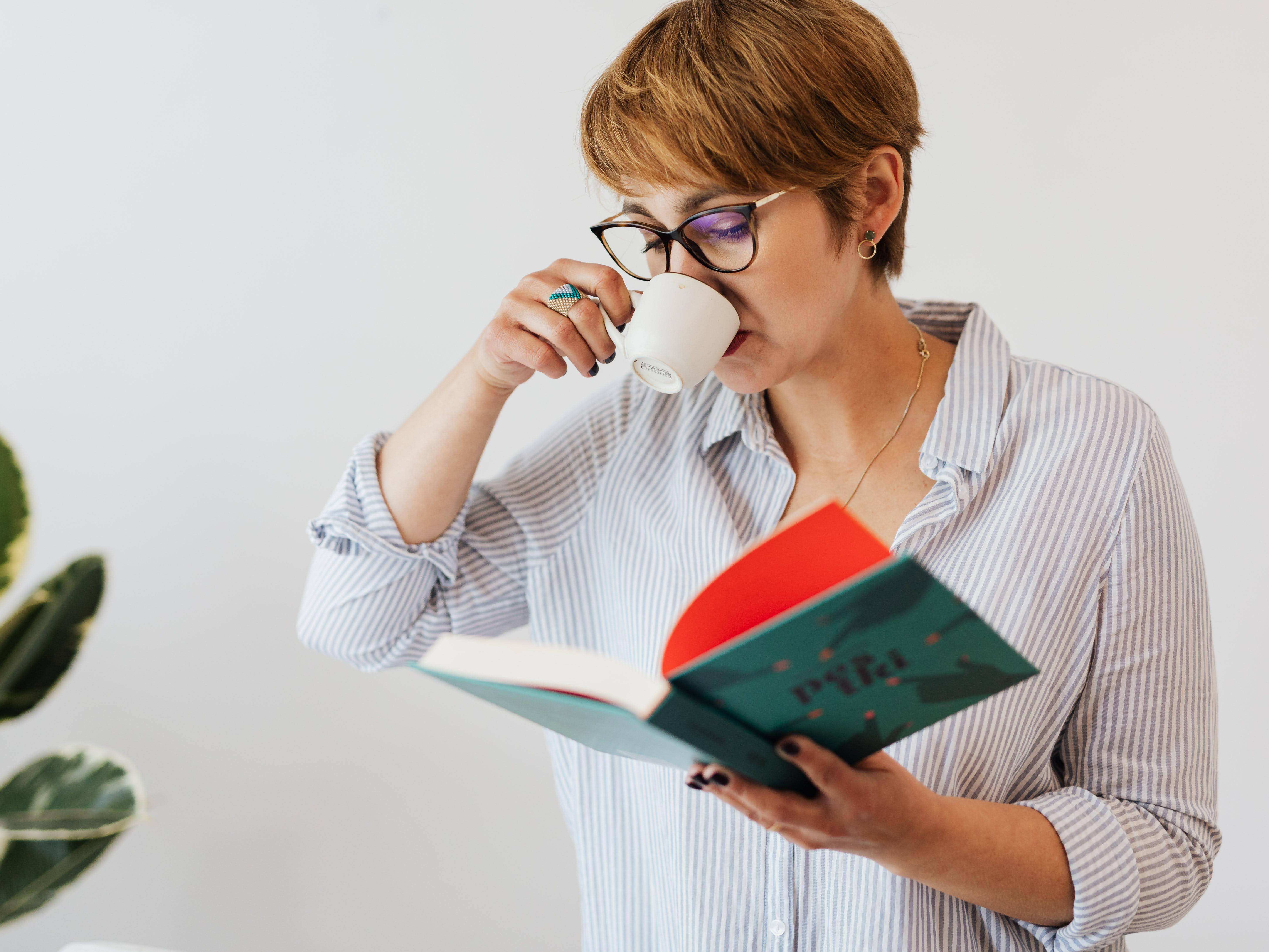 A Woman Drinking an Espresso While Reading a Book