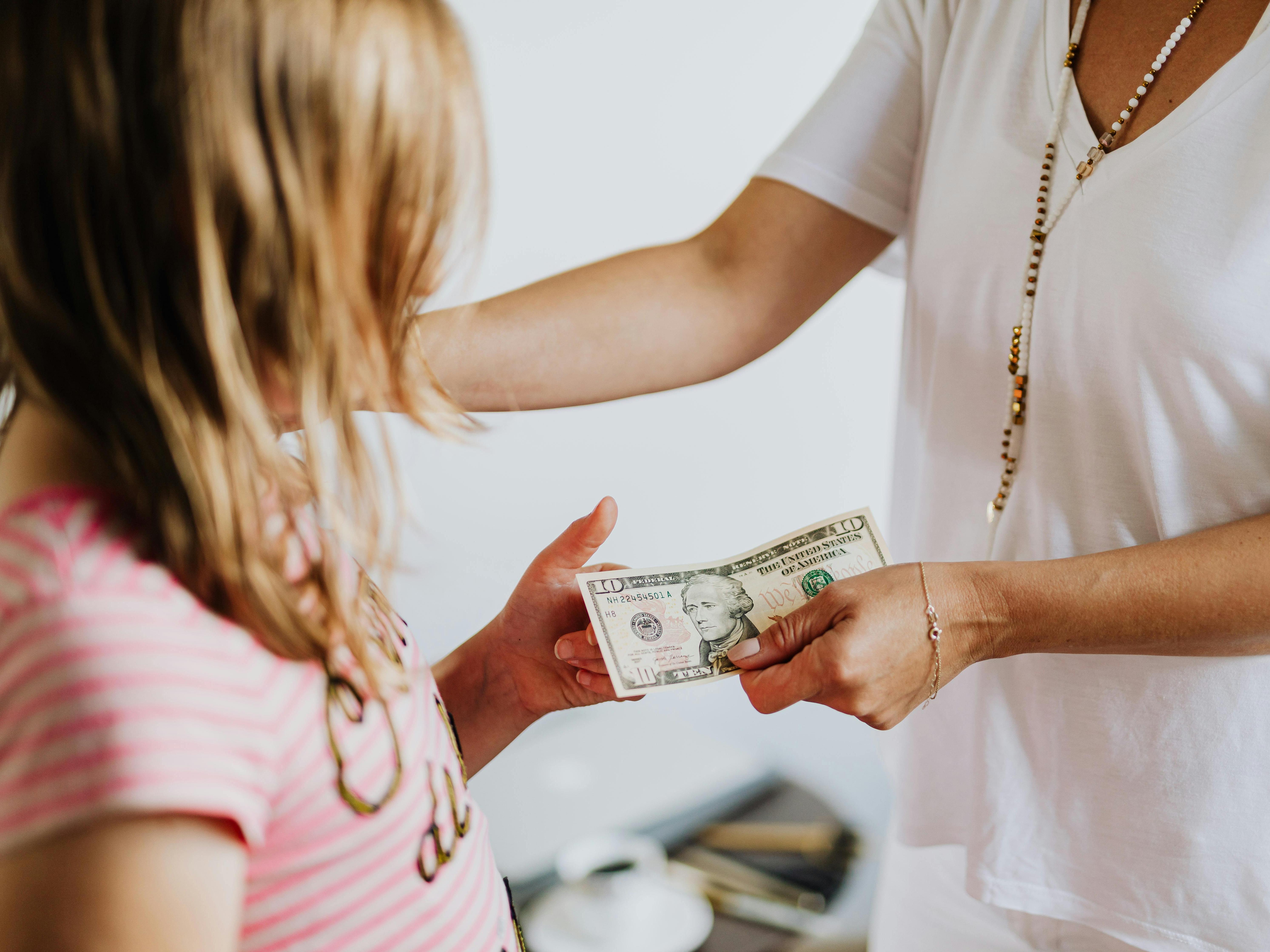 An Adult Giving a Ten-Dollar Bill to a Child