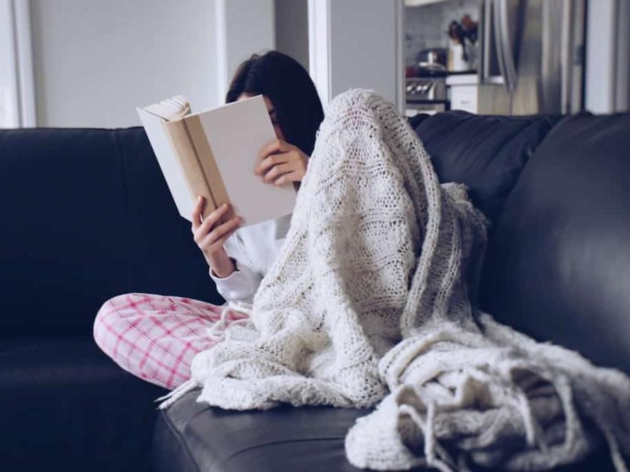 teen girl reading on sofa with blanket
